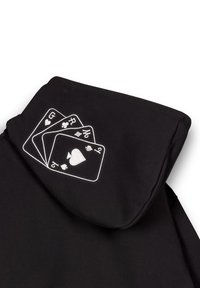 Schwarzer Kapuzenpullover mit einem gestickten Design von drei Spielkarten, die die Zahlen 2, 3 und G auf der linken Seite der Kapuze zeigen.