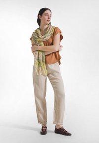 Ruskea lyhythihainen paita, kermanväriset pellavahousut ja kukkakuvioinen keltais-vihreä huivi. Asun täydentävät viininpunaiset nauhalliset kengät.