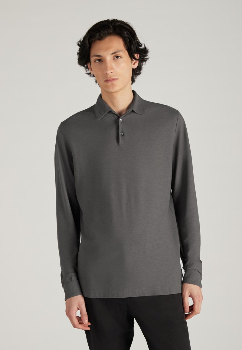 Koszula polo z długim rękawem w ciemnoszarym kolorze. Posiada kołnierzyk, trzy guziki przy zapięciu oraz luźny krój. Gładka tekstura.