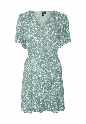 Groene korte mouw jurk met witte stippen, v-hals, knoopsluiting, strik taille en uitlopende rok. Lichtgewicht stof met een zachte textuur.