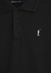 Zwarte polo met een gestructureerde stof, voorzien van drie zwarte knopen en een witte geborduurde golferlogo op de linkerborst.