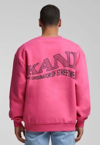 Rózsaszín, oversized fazonú pulóver, hátul fekete "KANDI" és "A STREETWEAR EREDETI" felirattal. Puha anyag, bordázott mandzsettákkal.
