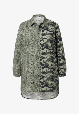Camisa verde y negra con diseño de botones, que presenta estampado de leopardo en un lado y camuflaje en el otro, mangas largas y dobladillo curvo.