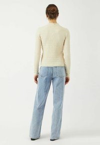 Krämfärgad, texturerad långärmad topp med en åtsittande design. Matchad med ljusblå vida jeans. Enkel och minimalistisk stil.