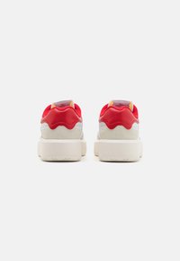 Czerwone i beżowe sneakersy z cholewką z nubuku i skóry, wyściełanym kołnierzem, grubą białą podeszwą oraz kontrastowymi akcentami kolorystycznymi na pięcie.