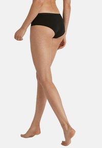 Slip da bikini neri realizzati in materiale morbido, con un design a vita bassa, copertura moderata sul retro e una semplice cintura elastica.