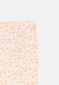 Λευκό ύφασμα με μικρό ροδακινί λουλουδάτο μοτίβο, δείχνει κοντινή λήψη της περιοχής της μέσης.