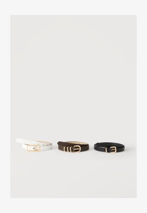 Trois ceintures en cuir roulées en blanc, marron et noir, chacune avec une boucle en or distincte, affichées horizontalement sur un fond blanc uni.