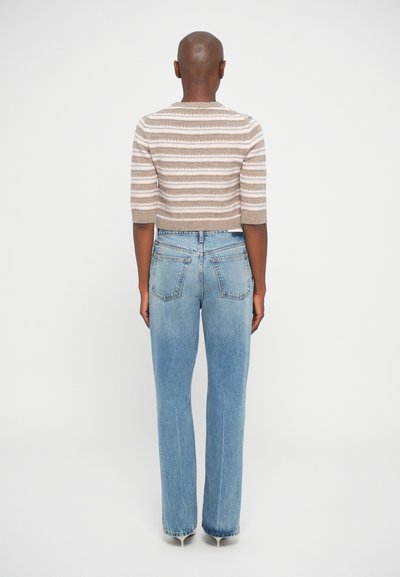 Pull court tricoté beige avec des rayures horizontales blanches, associé à un jean droit taille haute bleu clair.