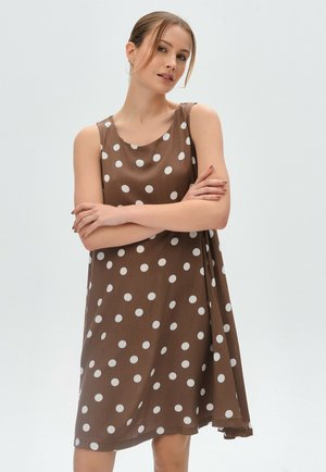 Braunes ärmelloses Kleid mit weißen Punkten, aus glattem Stoff. Es hat einen runden Ausschnitt und eine lockere, fließende Silhouette.