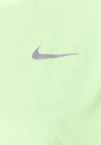 Srebrne logo Nike w kształcie łuku umieszczone na jasnoszarym tle.