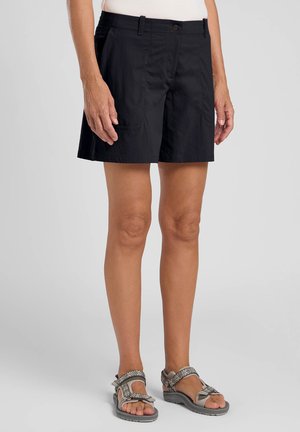 Pantaloni corti neri in tessuto leggero, con fronte piatto, due tasche laterali e chiusura con bottone. Abbinati a sandali grigi.