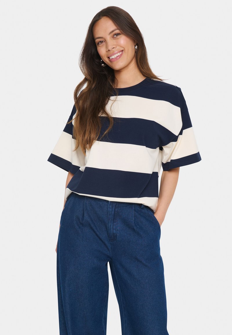 Navy and cream striped short-sleeve t-shirt with a crew neckline, made from a soft, textured fabric, paired with blue wide-leg trousers.