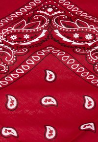 Červený bandana s bielymi paisley vzormi a kvetinovými akcentmi, s ľahkou štruktúrou, trojuholníkovým tvarom a kontrastnými obrysmi.