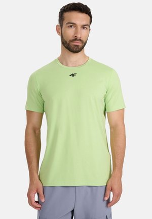 Jasnozielona koszulka z krótkim rękawem wykonana z miękkiej tkaniny, z okrągłym dekoltem i czarnym logo na piersi. Gładka faktura, dopasowany krój.