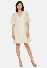 Kerge kreemikollane linane kleit lühikeste puhvsevarrukatega ja V-kaelusega. Sile tekstuur, millel on peen lillemuster.