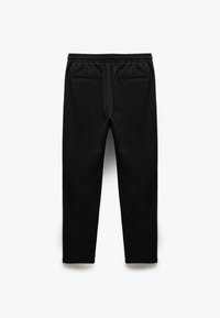 Pantalons de jogging noirs en tissu doux. Dotés d'une taille élastique, de deux poches latérales et d'un design de jambe fuselée. Texture lisse.