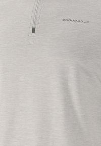 Vaaleanharmaa lyhythihainen polo, jossa on vetoketjukaulus, tehty sileästä ja hengittävästä kankaasta; varustettu hienovaraisella "ENDURANCE"-logolla.