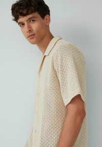 Kortelufthandt beige gebreide shirt met een textuurpatroon, kraagontwerp en knopen, met een open weving voor ademend vermogen.