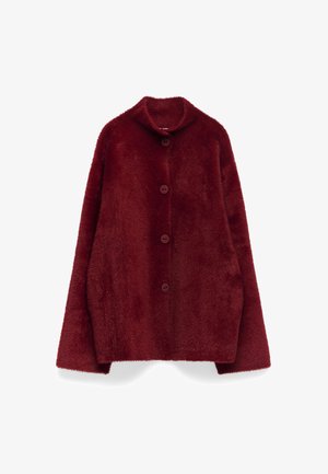 Burgundy faux fur-kappa med bred krage, fem stora knappar och lösa, förlängda ärmar. Mjuk textur med en plyschig utseende.