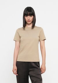 T-shirt beige a maniche corte in cotone. Presenta un colletto tondo e un discreto dettaglio del logo sulla parte anteriore. Texture liscia e omogenea.