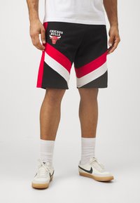 Črne kratke hlače z rdečimi in belimi diagonali, ki vsebujejo logotip "Chicago Bulls" na levem stegnu. Nosi se jih z belimi nogavicami in retro teniskami.