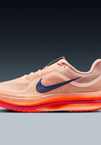 Zapatilla de running Nike de color rosa claro con malla transpirable, logo swoosh en azul oscuro y suela acolchada en naranja brillante y rosa sobre fondo gris.