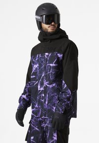 Zwarte en paarse skijack met een geometrisch patroon, voorzien van een hoge kraag, ritssluiting en logokleuren. Bijpassende handschoenen zijn inbegrepen.