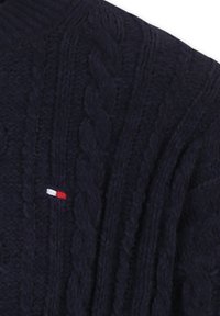 Suéter de punto de color navy con un prominente diseño de trenzado, que presenta un pequeño logotipo en rojo, blanco y azul en el área del pecho izquierdo.