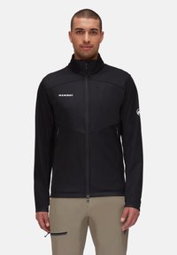Zwarte ritsjack met hoge kraag. Kenmerkt zich door een strakke ontwerp, twee zijzakken en een logo op de borst. Gemaakt van zachte, gestructureerde stof.