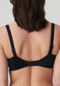 Mustat rintaliivit, joissa on säädettävät olkaimet, pitsireunus, sileä kankaan pinta ja takana hakasclosure.