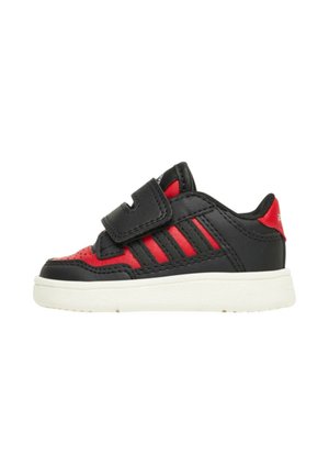 Baskets noires et rouges avec un design perforé, trois bandes noires, une sangle Velcro et une semelle blanche. Matériaux en cuir lisse et texturé.