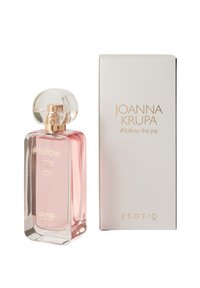 Flakon zapachu z przezroczystego szkła, w kształcie prostokąta, z jasnoróżowym płynem i okrągłym korkiem. Opakowanie białe z złotym napisem.