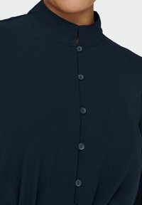 Marinskjorta med mandarinkrage, i strukturerad tyg och med fem matchande knappar fram.