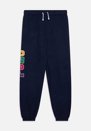 Donkerblauwe joggingbroek met elastische tailleband en boorden, witte koordsluiting en meerkleurige blokletters op één been.