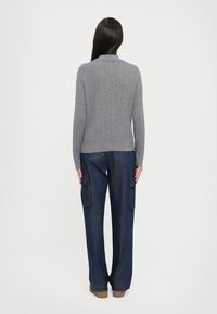 Grijze geribbelde trui met een kraag, gecombineerd met losse marineblauwe cargobroek met zijzakken en een rechte pasvorm.