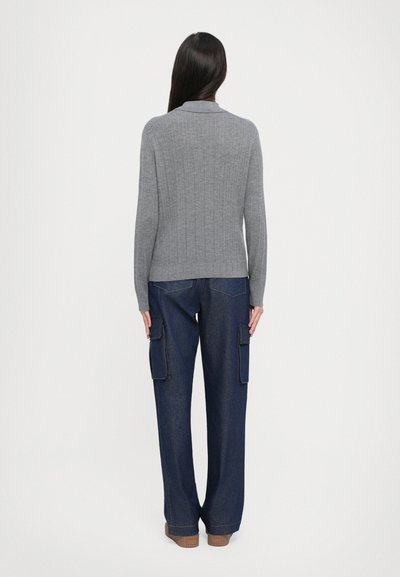 Šedý pletený svetr s límečkem, doplněný volnými námořnickými modrými cargo kalhotami s bočními kapsami a rovnými nohavicemi.