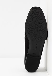Semelle noire d'une chaussure avec un motif ondulé, taille indiquée 4½, et nom de la marque Gabor visible sur fond blanc.