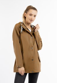Giubbotto impermeabile marrone con cappuccio, bottoni a scatto e due tasche laterali, caratterizzato da un rivestimento grigio e cordini decorativi.