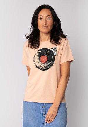 T-shirt en coton rose clair avec un graphique de disque vinyle noir, avec un centre rouge et un design de stylet imprimé sur la poitrine. Manches courtes.