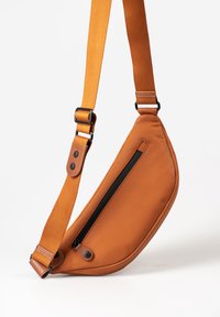 Borse a tracolla in pelle arancione bruciato con una forma curvata, tasca con cerniera nera e tracolla piatta regolabile. Finiture in metallo visibili.