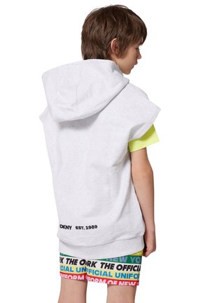 Sudadera sin mangas gris con una capucha grande, combinada con una camiseta amarilla brillante debajo. Presenta un logo impreso en la parte baja de la espalda.
