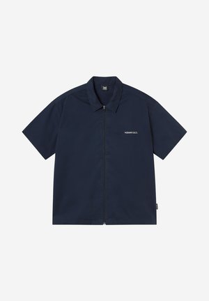 Μπλε σκούρο μπλουζάκι με κοντό μανίκι, γιακά και φερμουάρ μπροστά, με μικρό λευκό κείμενο "MORNING CALLS" στο αριστερό στήθος.