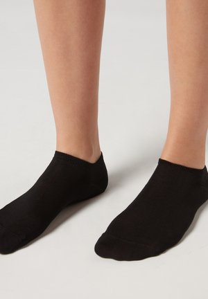 Calcetines negros hasta el tobillo con una textura acanalada, bordes lisos y un diseño ajustado que se adapta perfectamente al pie y al tobillo.