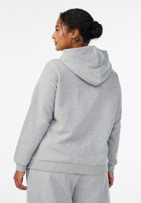 Felpa grigia con cappuccio a coulisse, tessuto morbido, polsini e orlo a coste. La parte posteriore presenta un design liscio, senza decorazioni.