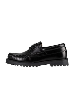 Scarpa in pelle nera con design moccasin, tomaia testurizzata, punta rotonda e suola in gomma spessa con battistrada decorato per una buona aderenza.