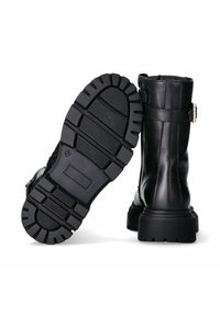 Stivaletti neri in pelle con suola in gomma spessa, caratterizzati da un motivo testurizzato con scanalature e un dettaglio con fibbia laterale.