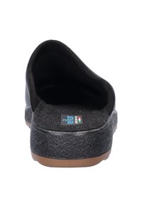 Zwarte instapper met een gestructureerde rubberen buitenzool, zachte voering en een ronde achterzijde. Heeft een merklabel dat zichtbaar is aan de binnenkant.