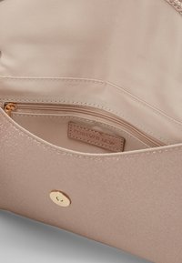 Wnętrze torebki w kolorze różowego złota o gładkiej satynowej fakturze, z kieszenią na zamek i wszytą etykietą „FOREVER NEW”.