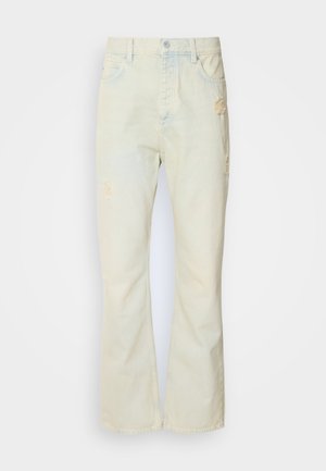 Svetlo bež ženske flare jeans hlače z raztrganimi zakrpami, zapiranje z gumbom in petimi žepi. Gladka tekstura in klasičen kroj.